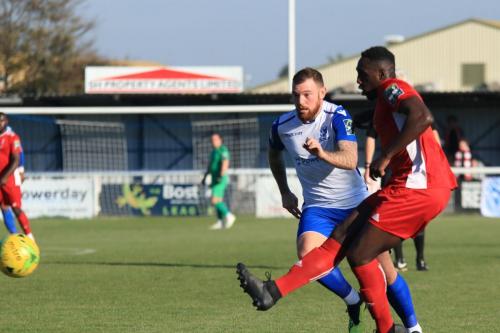Whitehawks aaron Goode (red) is pressured into a rushed backpass that beats his keeper but rolls just wide