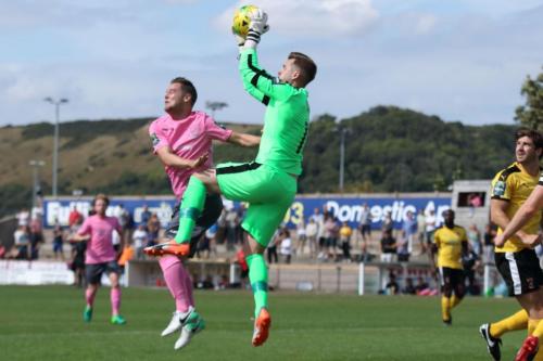 Folkestone keeper Tim Roberts catches a cross ahead of Liam Hope