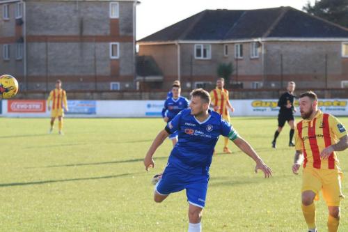Lowestofts Rossi Jarvis (L) heads clear from Billy Bricknell