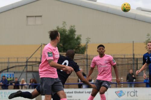 Wingates Marc Charles-Smith heads clear from Matt Johnson (pink, L)