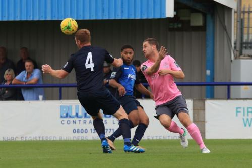 Wingates Marc Weatherstone (4) heads clear from Liam Hope
