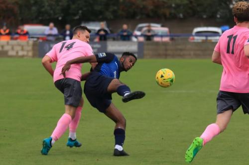 Wingates Reece Beckles-Richards (blue) clears from Brandon Adams