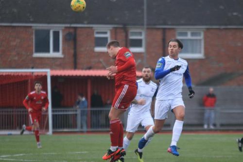 Worthings Joel Colbran (red) heads clear from Sam Youngs