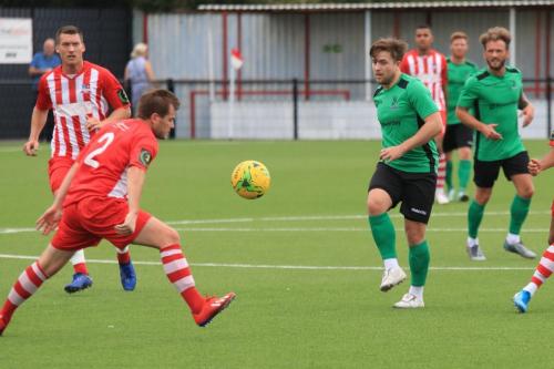 Enfields Lewis Taaffe (green, L) chips the ball forwards as Ryan Sammons tries to block