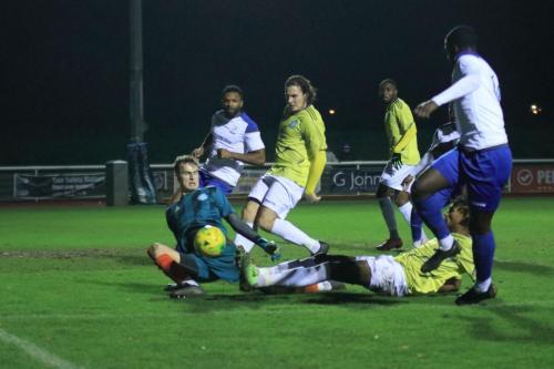 Staines Omar Ali (yellow, on ground) clears for a corner