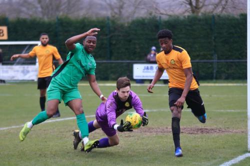 Merstham keeper Matte Pierson collects the ball ahead of Ken Charles (L) and Emmanuel Fernandez, although Charles had already been penalised for a foul