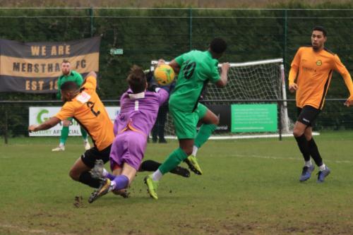 Merstham keeper Matte Pierson puncjhes clear from team mate Ellis Brown (L) and Ken Charles  The ball falls for Lyle Della-Verde to socre the third Enfield goal
