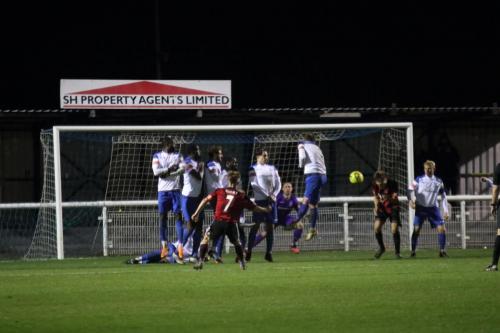 Brightlingsea's Kane Gilbert (7) takes a last-minute free kick. Note the defender lying behind the wall to block an attempt to shoot under the wall.