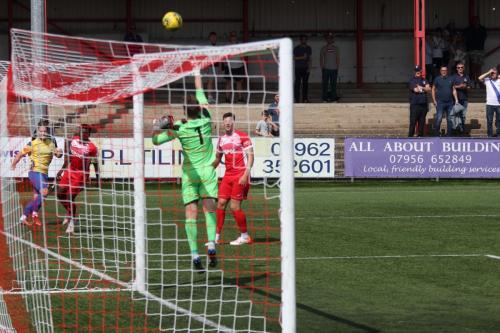Lewis Taaffe (yellow) slices an attempted cross/shot onto the roof of the Carshalton net