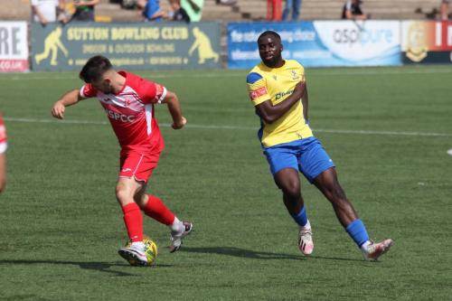 Carshalton's Tommy Bradford (L) beats Percy Kiangebeni to the ball