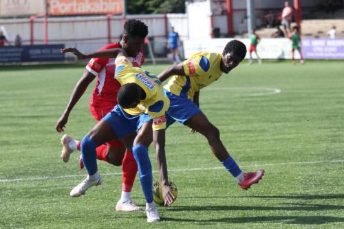 Carshalton's Paris Hamilton-Downes challenged by Muhammadu Faal and AndreCoker (R)