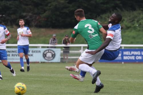 Dereham's Robbie Linford (green) body-checks Percy Kiangebeni