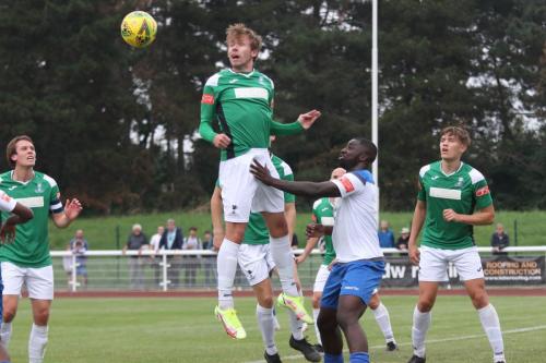Dereham's Rhys Logan heads clear from Percy Kiangebeni