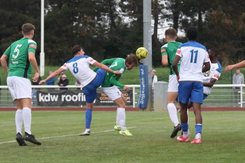 Dereham's Rhys Logan (green, centre) heads under pressure from Sam Youngs, who is penalised for a high foot