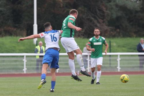 Dereham's Dion Frary (centre) heads clear from Lyle Della-Verde