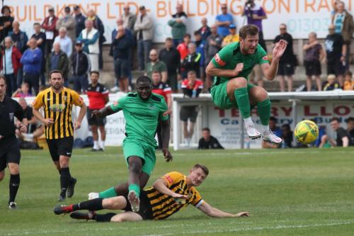 Enfield's Adam Cunnington (R) jumps out of the way of Percy Kiangebeni's shot
